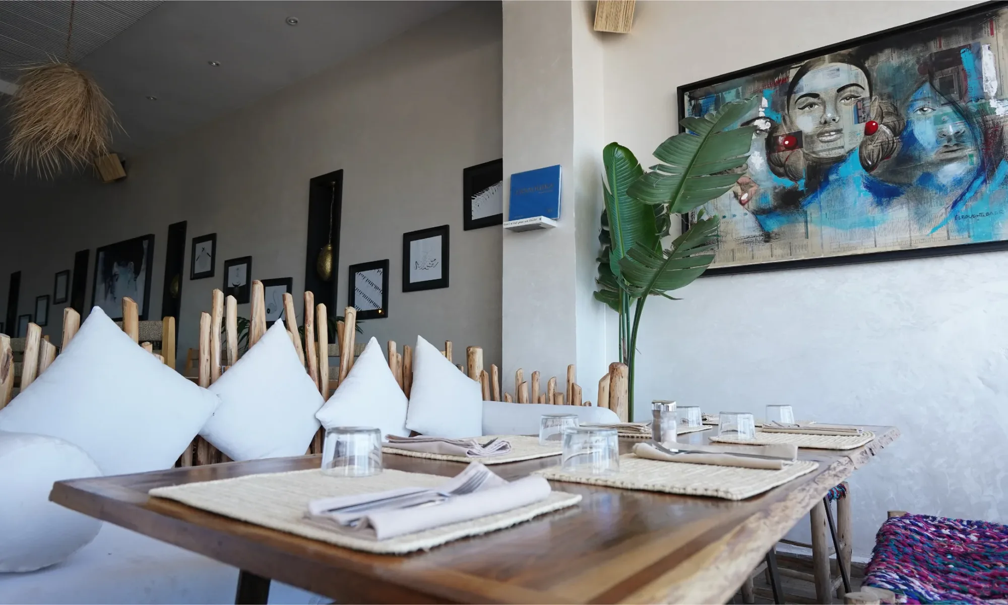 Salle de La Coupole avec ses cadres photo, ses coussins blancs et ses plantes tropicales