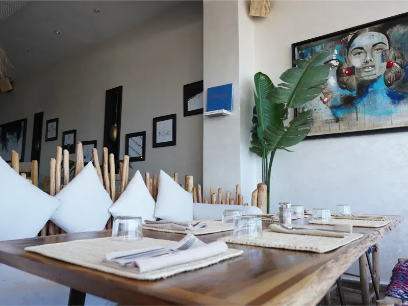 Salle de La Coupole avec ses cadres photo, ses coussins blancs et ses plantes tropicales