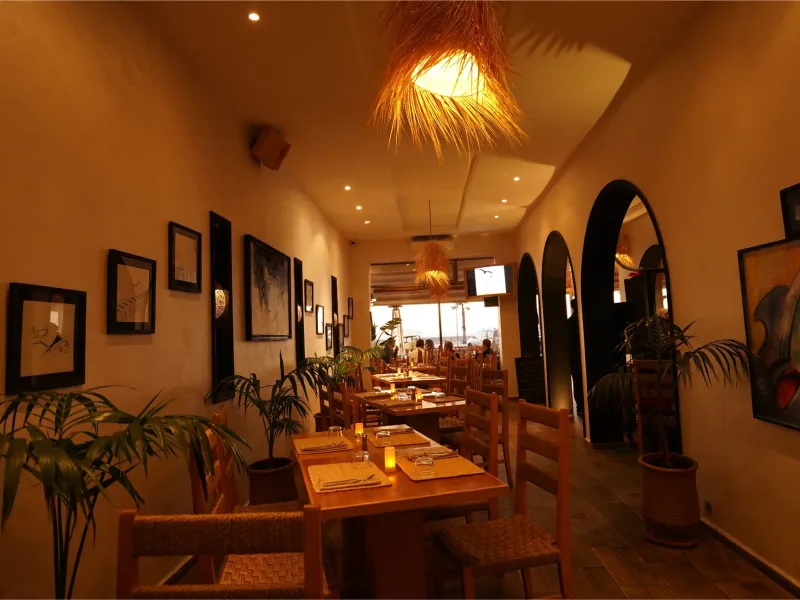 Salle du restaurant La Coupole à Essaouira, tables en bois et lumière chaude le soir