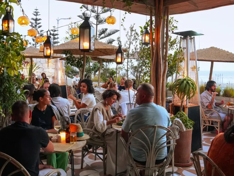 Convives en terrasse de La Coupole au coucher du soleil, corniche nord d’Essaouira