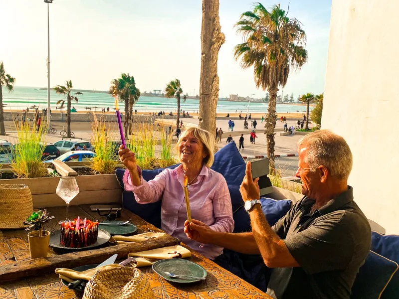 Couple trinquant en terrasse face à la plage d’Essaouira à La Coupole