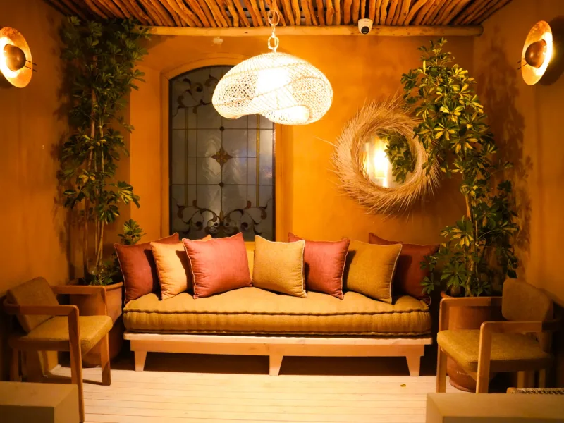 Salon aux coussins terracotta et suspension en rotin à La Coupole