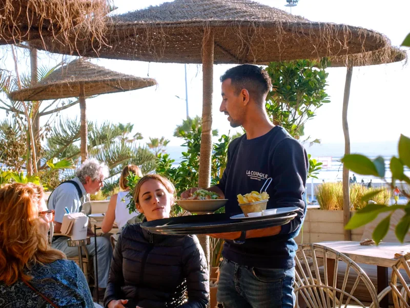 Serveur de La Coupole portant un plateau en terrasse
